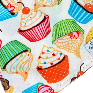 Colourful fabric with cartoon-style cupcakes and ice cream cones on a white background.