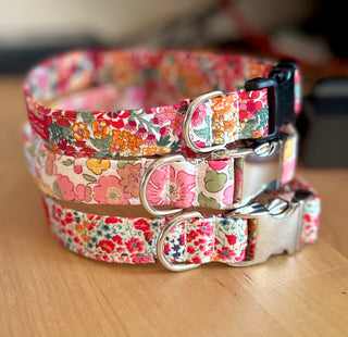 Three stacked handmade dog collars on a table, liberty flower fabric designs
